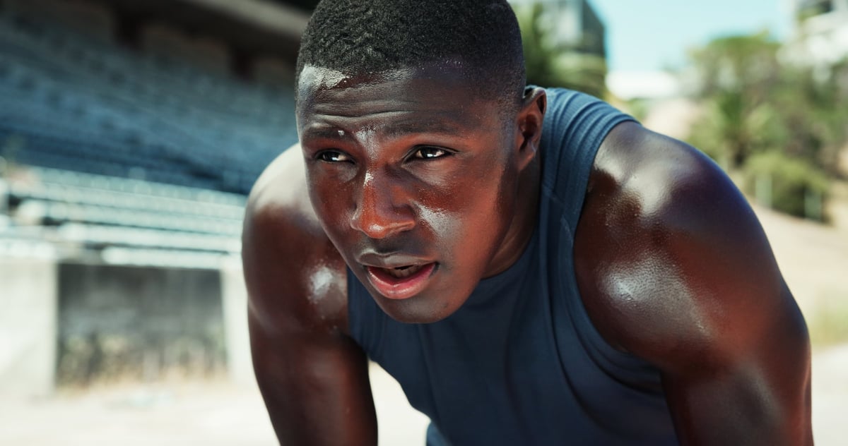 Fitness, black man and tired with breathing at stadium for race performance, endurance challenge and sweating. Runner, athlete and exhausted outdoor with running recovery, marathon rest and burnout